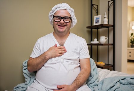 a pregnancy photo where a fully clothed emaciated man with Down syndrome is having a virtual self-care spa day.  No watermark, no signature.
