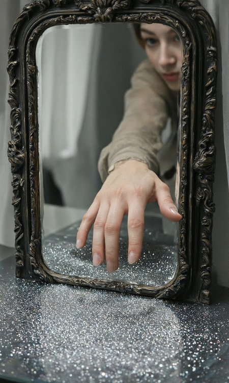 Style of Pierre Bonnard  with a surreal and magical aesthetic. The primary subject is a reflection of a hand in an ornate, vintage mirror. The hand, belonging to a person with fair skin, is reaching into a shallow pool of water that fills the bottom of the mirror. The water is covered in tiny, sparkling glitter particles, creating a shimmering, almost ethereal effect. The mirror itself has an elaborate, dark wooden frame with intricate carvings, adding to the vintage and antique feel of the scene. The background of the image is soft and blurred, with a hint of a white, sheer fabric or curtain draped behind the mirror, enhancing the dreamy atmosphere. The overall color palette is muted, with shades of gray, white, and black, creating a moody and otherworldly ambiance. The texture of the glitter in the water is smooth and reflective, while the mirror's frame has a rough, carved texture. The composition draws the viewer's eye to the hand reaching into the water, evoking a sense of curiosity and wonder. The overall style is a blend of fantasy and realism, with a focus on creating a visually captivating and whimsical scene., aidmaimageupgrader, aidmaMJ6.1