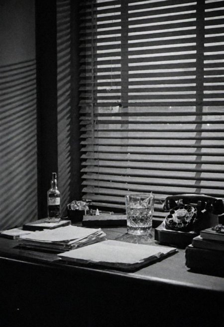 In the 1950s in Chicago, Night, interior of a private detective's office, desk on a bottle of Whiskey, cigarette smoke and little light coming through the blinds on the window. Captured on a 35mm camera, black and white, classic film.
inside