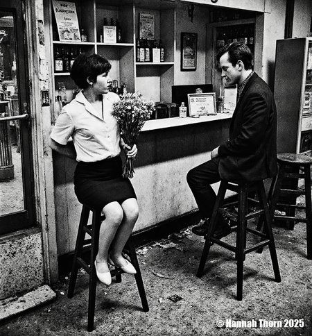A black and white photograph from the side, taken in an indoor location, depicting a casual scene of two people sitting at a counter in a bar. a woman with short hair, wearing a white blouse and a black skirt, sitting on a stool in the middle of the image, holding a bouquet of flowers in her hand. she appears to be in her mid-twenties, with a slim body and a serious expression. to her right, a man with short, dark hair is seated on a wooden stool, facing away from the camera, with his upper body visible. he is wearing a black suit and a patterned shirt, and is looking at the woman with a contemplative expression. the bar is cluttered with various items, including bottles and a vending machine, and the floor is covered in crumpled paper. the image has a vintage feel to it, with muted colors and a slightly blurred background.<lora:_Flux\Anders_Petersen.safetensors:0.9:0.9>