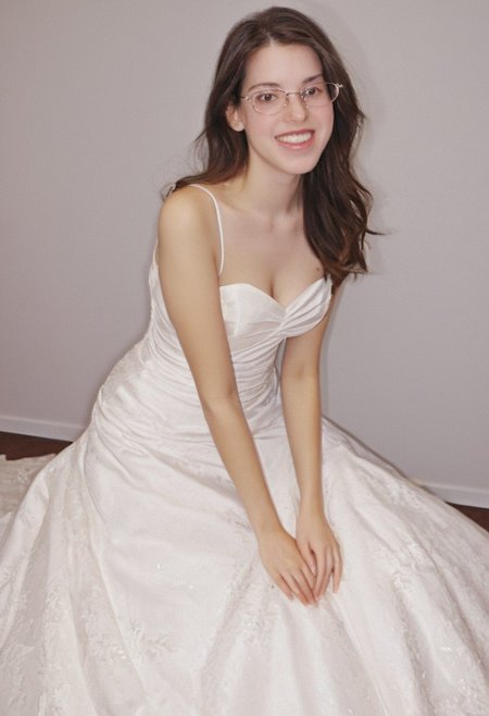realistic photo of Beautiful young woman, perfect medium perky natural breasts, 2009 style, low rise, low contrast style, 8mm film, analog photography style, long brown hair, sharp facial features,thick nerdy glasses, pale white skin, , influencer, brown eyes, no makeup, instagram, detailed skin texture, detailed eyes, detailed face, slim, (small waist, wide hips, thick thighs:1.2), (sexy wedding gown with pink highlights:2.0), happy, smiling, juicy ass,