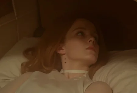 close-up shot of a young woman in a white nightgown lying flat on a bed in a victorian bedroom, staring upward at the ceiling with a sad expression, pale skin. Taken from the side, showing bite marks on the side of her neck. Soft warm light  <lora:hammer-000073:1>