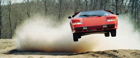 analog film photo car rally magazine photograph of a Rubine red Lamborghini Countach (((rally car))) jumping, big air time, rally jump, action motion blur dust LP5000 <lora:add-detail-xl:2> <lora:LP5000-SDXL-V1.2:1>, (big offroad lights at the roof:1.2), (hella flood lights, searchlights on roof:1.3) . faded film, desaturated, 35mm photo, grainy, vignette, vintage, Kodachrome, Lomography, stained, highly detailed, found footage