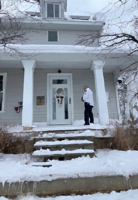 Stable_Yogis_SD1.5_Positives, patherpcook Stands in front of a House, Male, Strong, Flexing, Snow on head, Toga, Pondering, White house, Siding, walkway, driveway,
