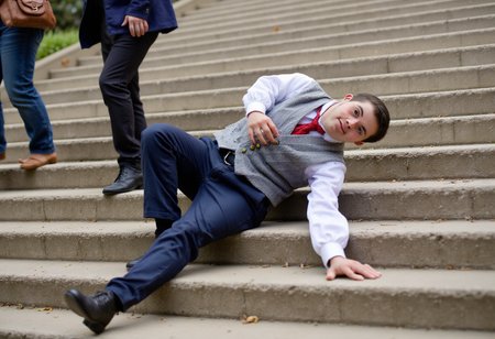 a casual photo where a dapperly dressed average superhero with Down syndrome is Falling down the stairs in public.  No watermark, no signature.