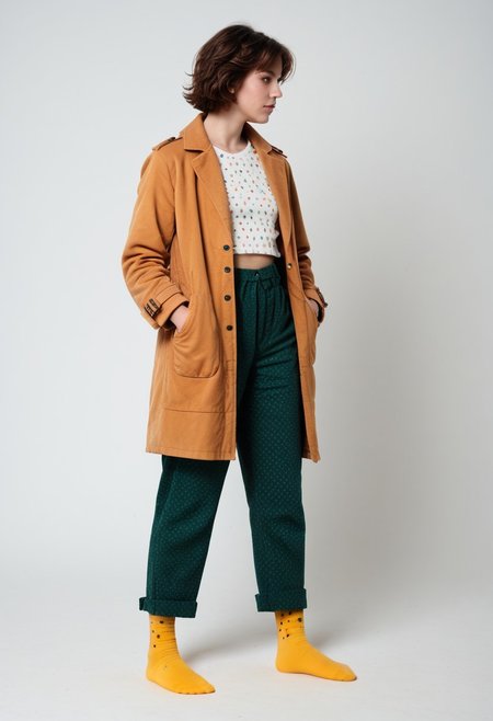 (realistic photograph of woman), 1girl, solo, simple_background, white_background, scksnsndls, patterned red and yellow socks, green trousers, orange and brown coat, short_hair, looking_away, full_body, (birksonsocks, birkenstock)