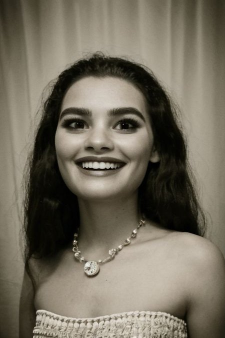 fFaceDetail,  bare_shoulders, long_hair, lips, bead_necklace,1girl, lips, solo, flower in hair, breasts,  formal dress, film grain, lip bite expression, monochrome,  lipbite, portrait, 1950's hairdo, formal hairstyle, glamour,  cleavage:1.7, headshot, realistic, photograph, 8k, sexy, (looking at viewer), bokeh background, smile, grin, satin, eye focus, biting lips, greyscale