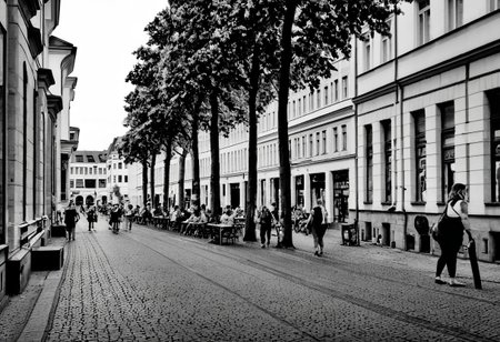 monochrome, instagram photo, a street in leipzig where i can see the westwerk on the right side. it's a summery atmosphere, in the afternoon at 16:00 and there are many people walking around on the street.