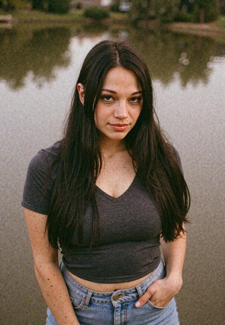vintage film photography, young woman, long dark hair, fitted shirt, fitted jeans, full hips, piercing eyes, soft natural lighting, muted color tones, moody aesthetic, candid expression, shallow depth of field, retro ambiance, warm skin tones, artistic composition, timeless style, nostalgic atmosphere, soft focus edges, outdoors, natural lighting, light-smile <lora:Mona_Azar_Flux_r1:1.0> <lora:#phonelqstyle_r15:0.3>