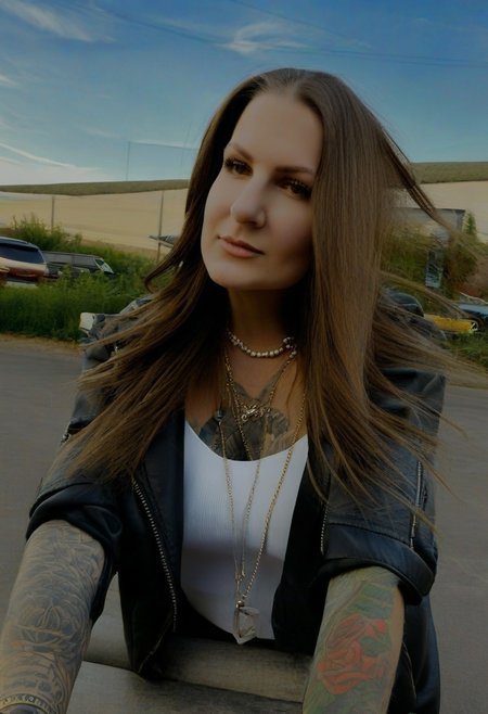 1girl, solo, tattoo, jewelry, realistic, brown hair, necklace, jacket, long hair, photo background, looking at viewer, outdoors, motor vehicle, arm tattoo, gnsuh