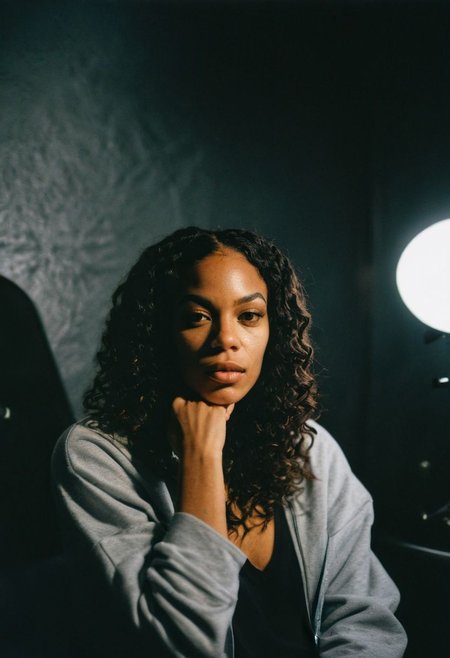 (gritty analog photo:1.2), candid (snapshot:1.2) of a sophisticated and cool 22-year-old biracial female hip-hop artist from Brooklyn sitting in a backstage room getting ready for her show, natural skin texture, realistic skin texture, (skin pores:0.8), (skin oils:0.8), (behind the scenes photography:1.2), documentary style photography, high contrast, deep shadows, hires, highly detailed, (film grain:1.2), the picture conveys effortless coolness, polaroid film photography