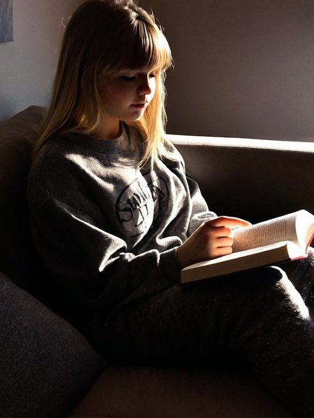 Cinematic fashion photograph  Adeera_Addams_P_MXAI_SDXL , wearing comfortable clothes, sitting on a couch, reading a book, shadows, relaxed, elegant,