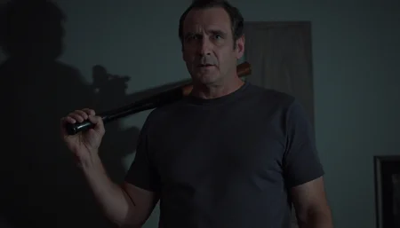cinematic medium shot of a 50 y.o. man standing in a living room at night, scared expression, holding a large baseball bat, wearing a t-shirt and boxer shorts. He is lit by a flash light, casting a large shadow on the wall behind him. Cold direct artificial light. High resolution. 2020s movie <lora:dark_cinematic-000080:1>