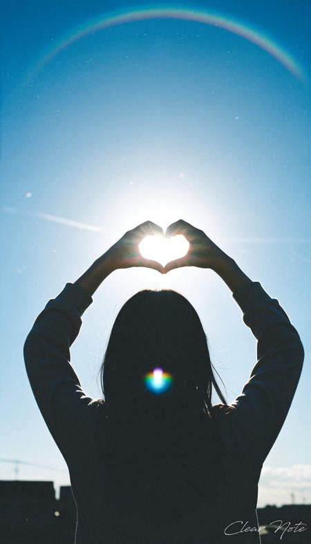 Japanese Culture Style, Emotional Photos, 35mm film, Back view of a Japanese woman making a heart symbol with her hands facing the blue sky and sun
