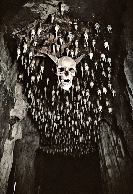 antique photo, eerie atmosphere, creepy, cave, descent into madness, lovecraft horror, walls made of skulls, one bat hanging from the ceiling, <lora:Antique_Photo:1>