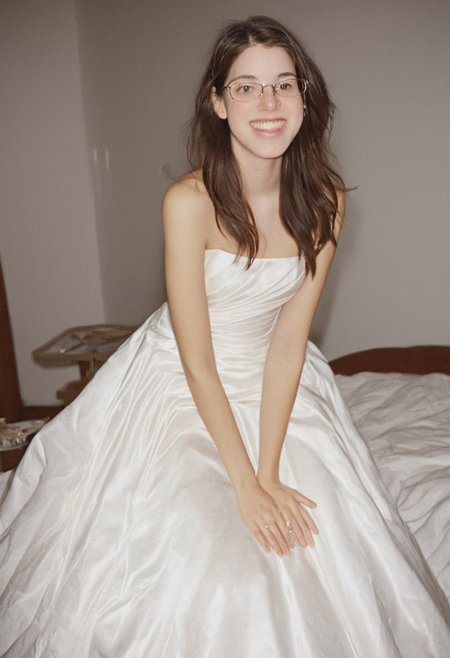 realistic photo of Beautiful young woman, perfect medium perky natural breasts, 2009 style, low rise, low contrast style, 8mm film, analog photography style, long brown hair, sharp facial features,thick nerdy glasses, pale white skin, , influencer, brown eyes, no makeup, instagram, detailed skin texture, detailed eyes, detailed face, slim, (small waist, wide hips, thick thighs:1.2), (sexy wedding dress:1.3), happy, smiling, juicy ass,