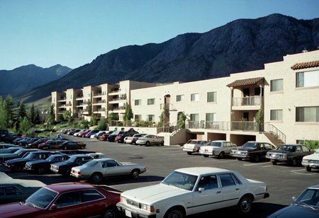 parking lot, cars, condos, mountains, outdoors, highly detailed, 4K, (grainy analog 35mm photo)