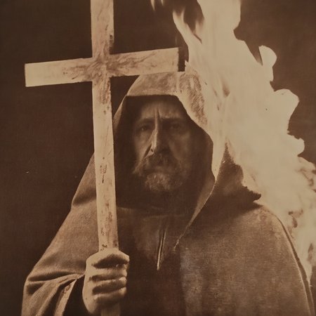 nostellum close-up of an inquisitor man in a cloak with a large cross, in the background burning sacrificial pyre , a burning persona<lora:nostellum:1>