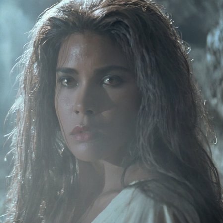 Horror-themed,  <lora:Fright Night 1985 Film Style:1>
Cinematic Closeup Shot Film Footage captured by Panavision Cameras, Regine Dandridge a sexy white cave woman with long messy hair and an innocent look on her face staring at someone to the left with cool light onFright Night 1985 Film Style, Eerie, unsettling, dark, spooky, suspenseful, grim, highly detailed