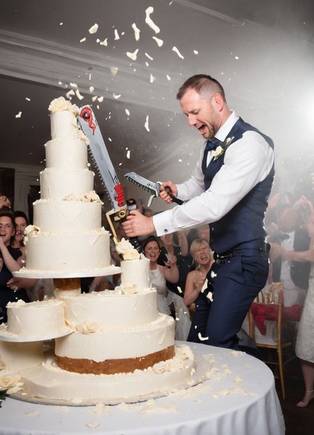 groom cutting a big wedding cake with  a 40kchainsword, cream flying everywhere, 
 <lora:Chainsword_-_Warhammer_40000_SDXL:0.8>