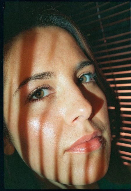 35mm film sample image, Close up shot of a 33 years old woman face, harsh low-key lighting, blinds shadows on her face, high contrast, Grainy, Lomography, lomoChrome, Analog Film, Kodak Ektar 100, Cinematic composition, Rule of thirds