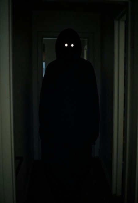 horroreyeshine, horror (theme)
,The image is a dark, eerie photograph depicting a haunting scene. The subject is a tall, gaunt figure of a woman standing in a dimly lit, narrow hallway.