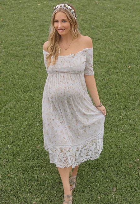 Masterpiece, detailed, realistic photo, standing, front_view, mature woman, fully_dressed, 44 years old, solo, soft sunlight, serene expression, flowing locks, floral headband, off-the-shoulder top, billowing sleeves, delicate lace details, dainty necklace, freckles dusting across nose and cheeks, rosy lips, gentle smile, bohemian skirt swaying around hips, wide hips, bare feet grazing over grass, peaceful contemplation, huge_breasts, Ultra detailed photo realistic background, realistic high detailed face, anatomic correct bodies, extremely realistic, lots of detail, strong, athletic, seductive, a little plump, many wrinkles, hands hidden or out of view, just pregnant, blue eyes.