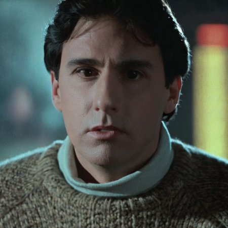 Horror-themed,  <lora:Fright Night 1985 Film Style:1>
Cinematic Closeup Shot Film Footage captured by Panavision Cameras and Lenses, Jerry Dandrige a man in a turtle neck sweater looks off to the side with blur background Fright Night 1985 Film Style, Eerie, unsettling, dark, spooky, suspenseful, grim, highly detailed
