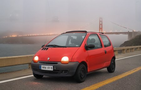 golden gate bridge at night, foggy, a black renault twingo car , red headlights, black wheels,  from the front, headlights shining through the fog , horror movie atmosphere<lora:Twingo_SDXL:1>