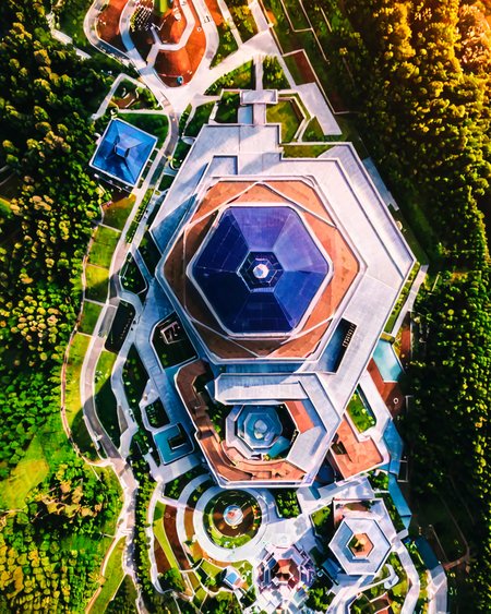 vertical perspective aerial photography, unique_architecture, building, geometric_design, surrounded_by_trees, nature, landscape, <lora:sky:0.8>