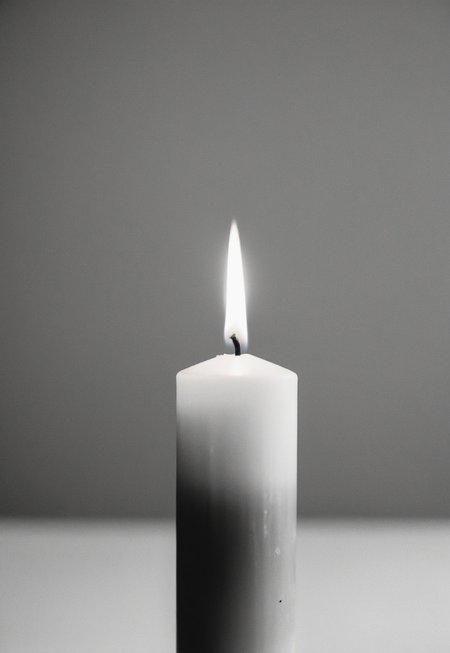 Close up of a Unique Looking Candle in the middle on a Black Table, Completely white background, Soft diffused lighting, grayscale, Monochromatic, Muted Tones, Minimalist, Ethereal, Leica MP, Leica Noctilux 50mm f0.95  Lens, Kodak Tri-X 400 Film, 35mm Film, Film Grain, Film halation