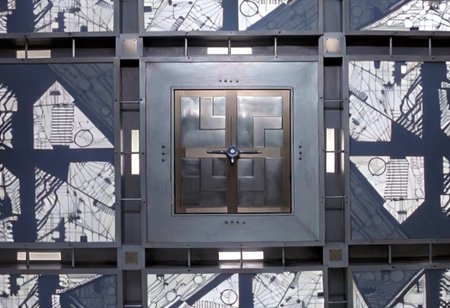 *A futuristic, cubic room where every surface—the floor, walls, and ceiling—looks identical, creating a symmetrical and disorienting space. The room is made of metallic panels, each featuring intricate, geometric patterns resembling advanced circuitry. These patterns are precisely cut into the metal, allowing a soft, white light to filter through, casting sharp, complex shadows across the surfaces. The cold, white light gives the room a sterile, almost otherworldly feel. The metallic surfaces subtly reflect the light and patterns, amplifying the sense of depth and making it difficult to distinguish one wall from another.
In the center of each of the six surfaces, including the floor and ceiling, is a square metallic door, seamlessly integrated into the surrounding panels. These doors are identical and blend into the room’s design, adding to the disorienting and claustrophobic atmosphere. The uniformity and symmetry of the room create a high-tech, sterile environment that feels isolating and mysterious.
The overall ambiance is one of eerie sophistication, blending advanced technology with unsettling uniformity. The space feels like a confining, enigmatic environment where every direction is the same, leaving anyone inside with a sense of isolation and uncertainty. Each surface of the room looks exactly the same. The room is 5 meters long in each direction.*
