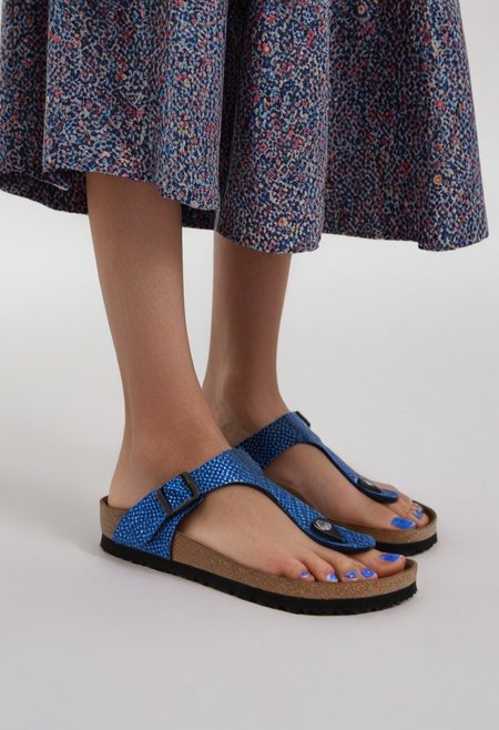 1girl, solo, dynamic_pose, simple_background, white_background, gizehonfeet, blue_toenail_polish, close-up, lower_body, footwear_focus, patterned, long_skirt
