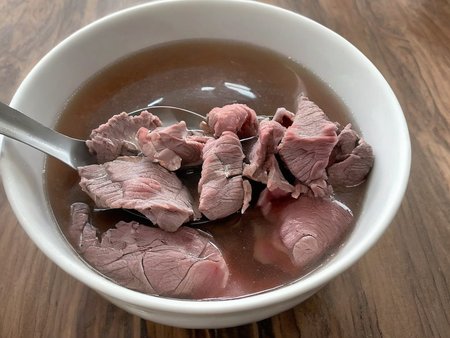A high-resolution, hyper-realistic image of a bowl of Sweetbeefsoup. This traditional dish features a clear, sweet broth that is the star of the dish. The broth is simmered to perfection, with a hint of sweetness that tantalizes the taste buds. A subtle hint of pink is added to the broth, giving it a unique and appealing look. It's served in a traditional ceramic bowl, placed on a rustic wooden table. The scene is set in a cozy kitchen, with all elements in sharp focus, creating a clear and detailed image. The lighting should be warm and inviting, highlighting the appetizing qualities of the Sweetbeefsoup and the homely atmosphere of the setting, <lora:beefsoup:0.8>