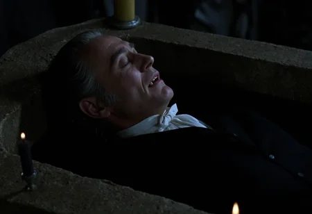 medium shot of a middle-aged aristocratic vampire man lying in a stone sarcophagus asleep with closed eyes, pale skin, showing fangs, grey hair slicked back, dark victorian suit, surrounded by candles, taken from above, low light at night <lora:hammer-000073:1>