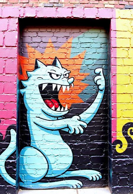 <lora:Brick_Wall_Graffiti_FLUX:1>
This is a vibrant, detailed photograph of a mural painted on a brick wall. The mural features a stylized, cartoonish depiction of  an angry cat hissing
