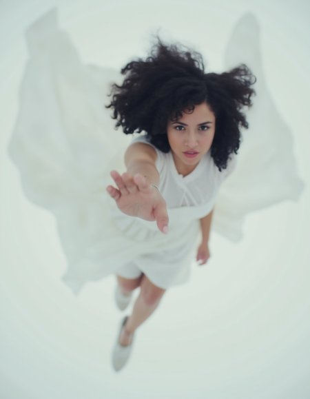 women falling down, hand in the air facing the viewer, black curly hair, white dress flowing in the wind, cinematic, majestic, blank background,  <lora:CinematicStyleFlux_v1:1>   <lora:FLUX.1d_-_Blurry_Photos:1> blurfoto , top view,